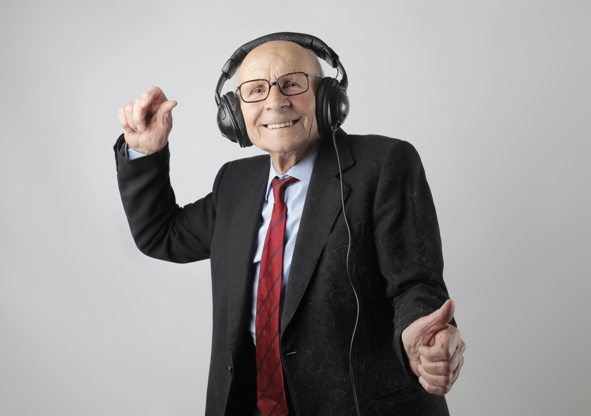Elder man wearing headphones with coat and tie