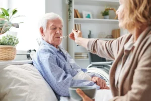Smiling elderly woman sitting at table holding a cup in a bright home space